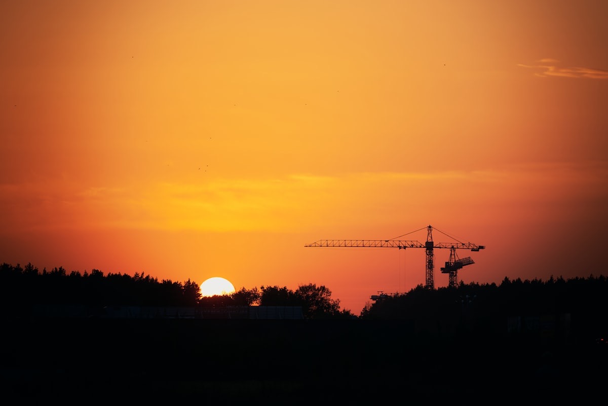 夕陽と遠くのクレーンが見える現場の風景（イメージ写真）