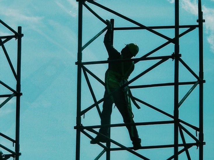 足場の上で作業する建築施工スタッフのシルエット（イメージ写真）